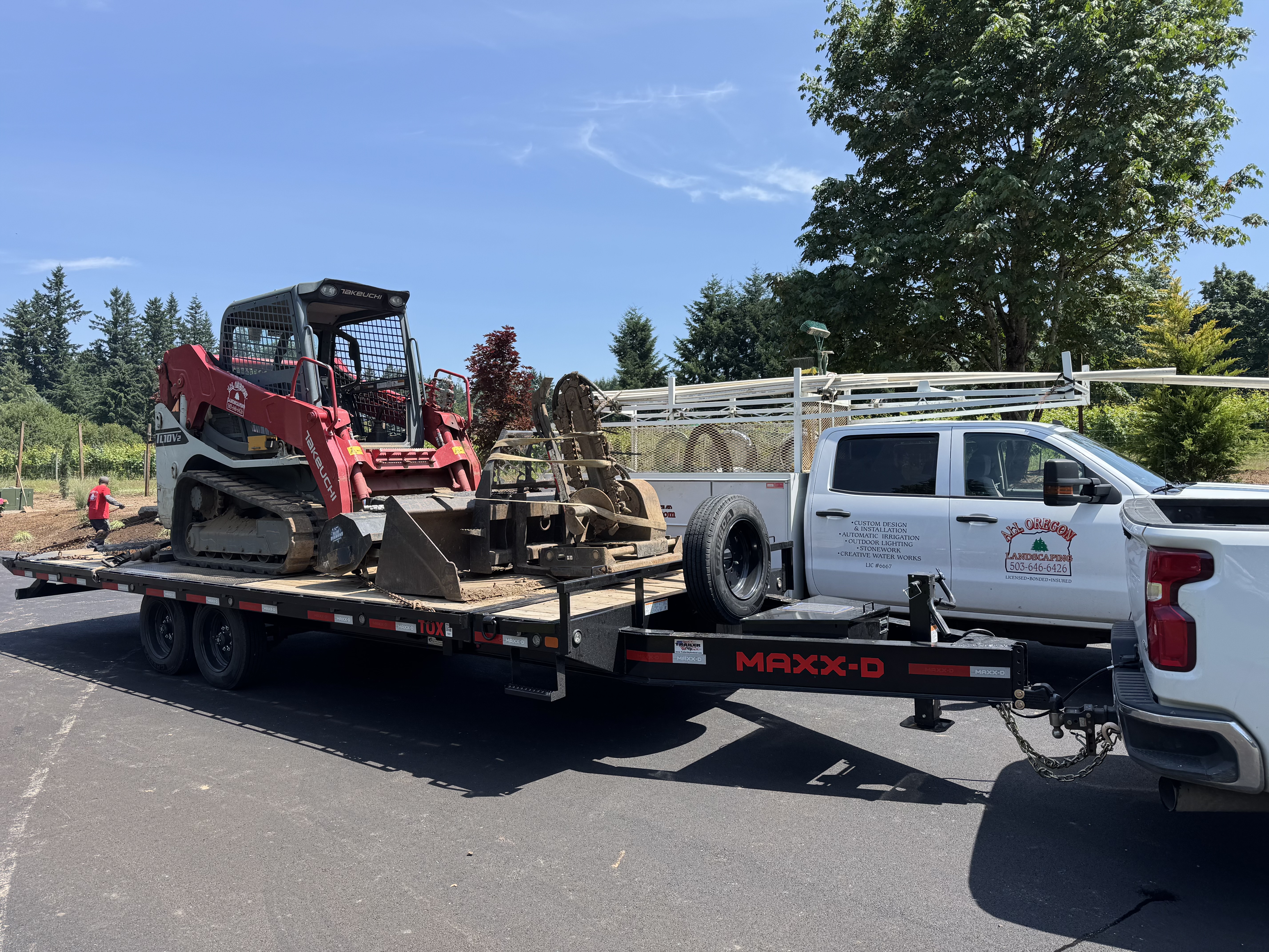 Tracked loader and attachments on a MAXXD deckover trailer connected to a pickup